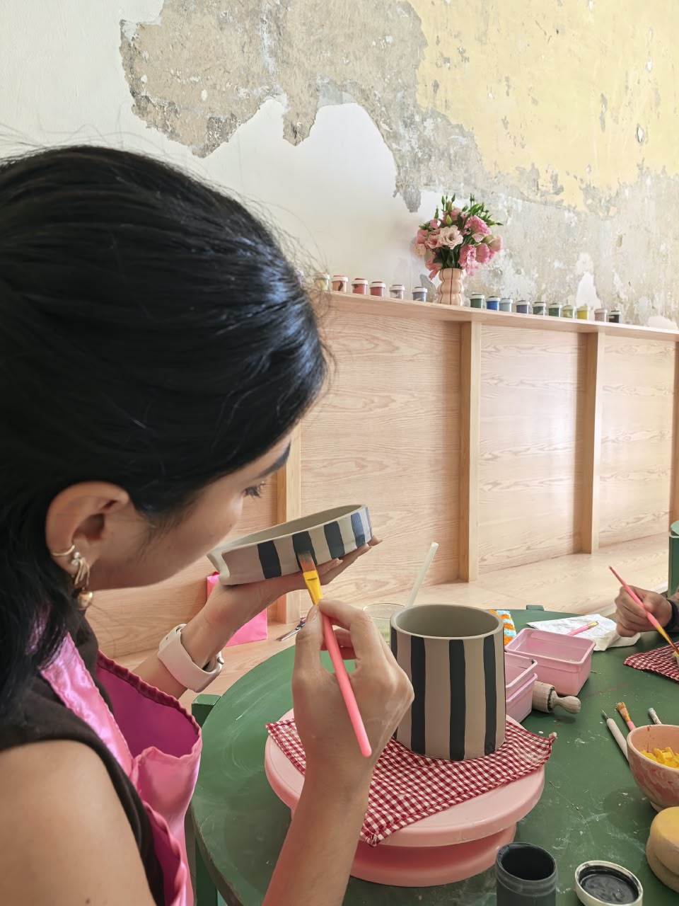 Una persona pintando una taza de cerámica durante un taller de Venusiana